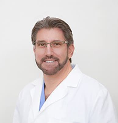 Friendly pictured portrait of Dr. Robert Kaufman, a skilled dentist at Lifeway Dental of Boca Raton, smiling with arms crossed in his lab coat.